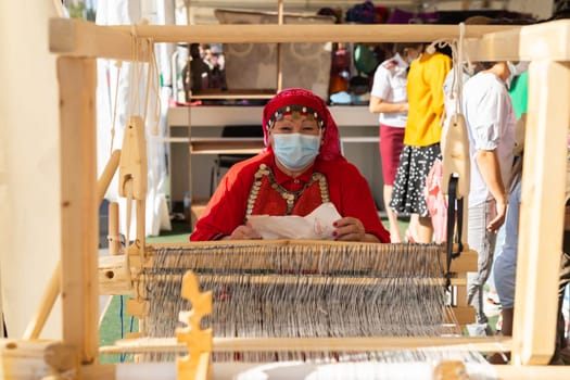 UFA, RUSSIA - JULY 10, 2021: Bashkir woman make carpet during Folkloriada in Ufa