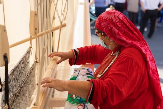 UFA, RUSSIA - JULY 10, 2021: Bashkir woman make carpet during Folkloriada in Ufa