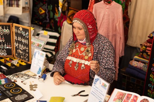 UFA, RUSSIA - JULY 10, 2021: Bashkir woman make carpet during Folkloriada in Ufa