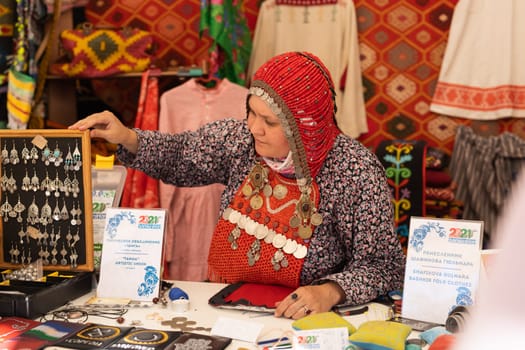 UFA, RUSSIA - JULY 10, 2021: Bashkir woman make carpet during Folkloriada in Ufa