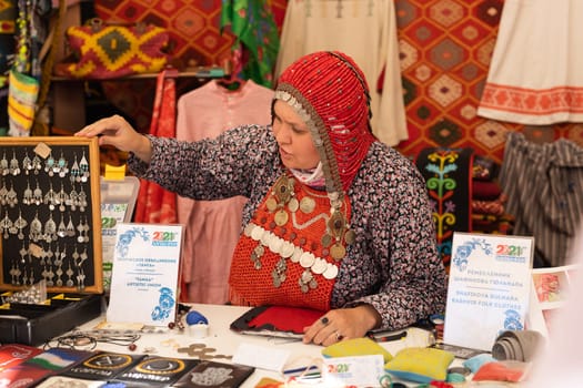 UFA, RUSSIA - JULY 10, 2021: Bashkir woman make carpet during Folkloriada in Ufa