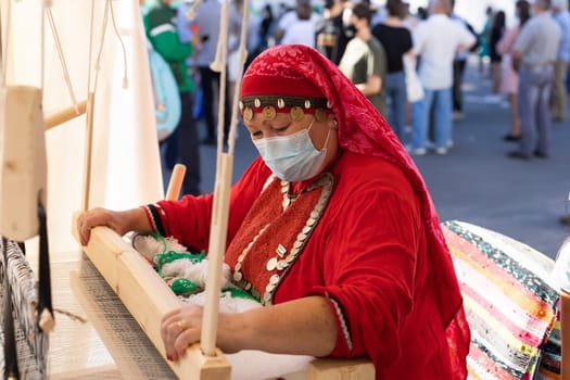 UFA, RUSSIA - JULY 10, 2021: Bashkir woman make carpet during Folkloriada in Ufa