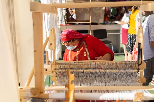 UFA, RUSSIA - JULY 10, 2021: Bashkir woman make carpet during Folkloriada in Ufa