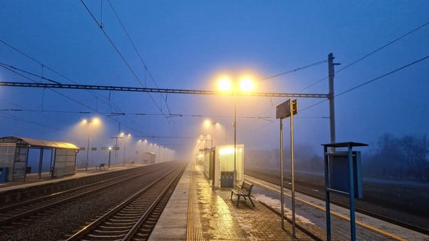 Night railway terminal. Deserted train station in fog. Concept of travelling, tourism or commuting to work.