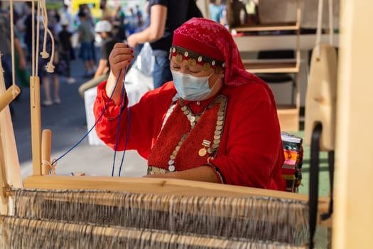 UFA, RUSSIA - JULY 10, 2021: Bashkir woman make carpet during Folkloriada in Ufa