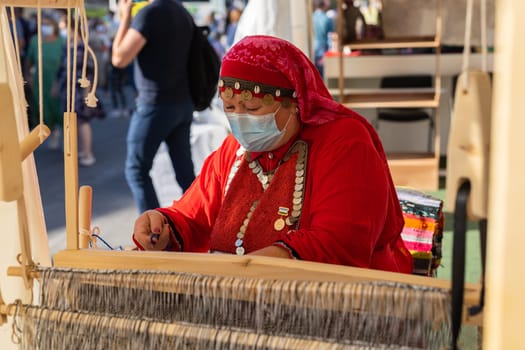 UFA, RUSSIA - JULY 10, 2021: Bashkir woman make carpet during Folkloriada in Ufa