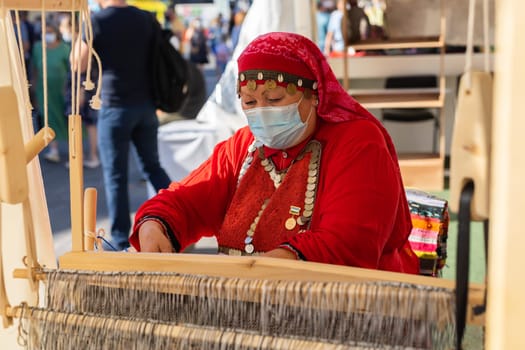 UFA, RUSSIA - JULY 10, 2021: Bashkir woman make carpet during Folkloriada in Ufa