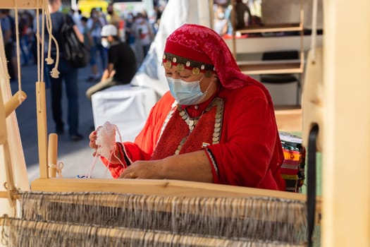 UFA, RUSSIA - JULY 10, 2021: Bashkir woman make carpet during Folkloriada in Ufa