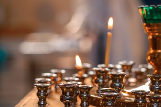 Burning candles on a lamp in a Christian Orthodox church, close up, copy space.