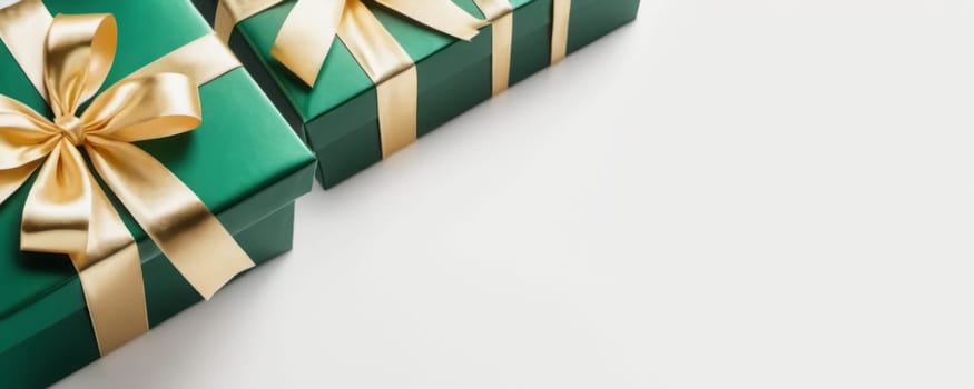 Two green gift boxes with golden ribbons on a white surface, perfect for festive occasions