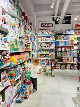 Little girl chooses a toy set on a store shelf. High quality photo