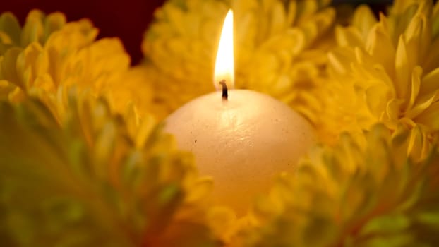 Celebration of the religious Indian festival of Diwali. Yellow flowers with burning holi candles at Hindi festival close-up