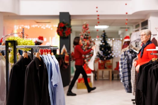 Old client searching for formal attire in clothing store, buying clothes from clearance section at shopping center. Woman looking for gifts during christmas holiday, giving presents to family.