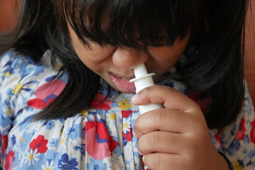 close up of sick child using nasal medicine spray.