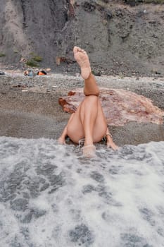 Woman travel sea. Young Happy woman in a long red dress posing on a beach near the sea on background of volcanic rocks, like in Iceland, sharing travel adventure journey