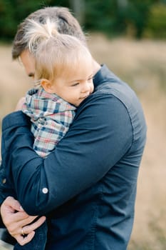 Dad hugs a little girl holding her in his arms. Side view. High quality photo