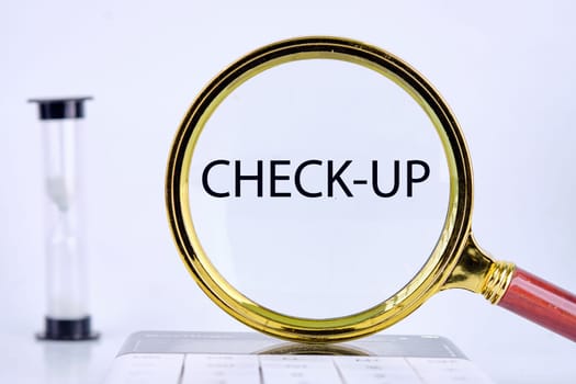 CHECK-UP text, word, inscription found through a magnifying glass next to an hourglass on a light background