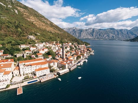 St. Mark Church on the square among old houses with red roofs on the shore of the bay. Perast, Montenegro. Drone. High quality photo