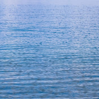 Blue sea in sunshine glow as surface background. Summer holidays and coastal nature concept