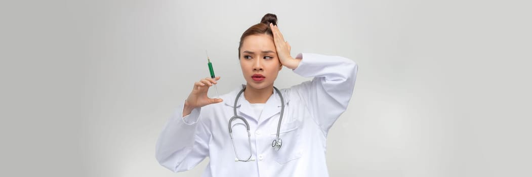 Young woman holding syringe stressed and frustrated with hand on head, surprised and angry face