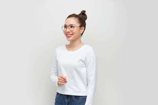 Smiling, beautiful asian posing on a white wall. Young woman is standing at blank wall.