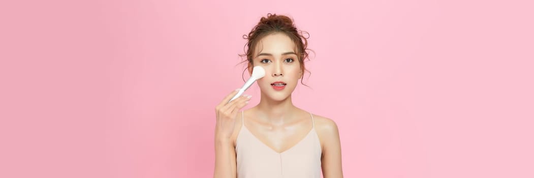 Beautiful Asian young woman smile and holding make up brush with healthy Clean and Fresh skin 