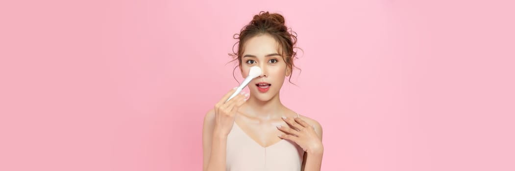 Closeup Beautiful  asian woman applying makeup with Cosmetic Powder Brush