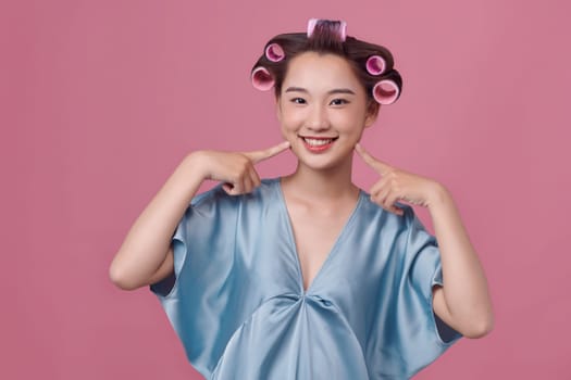 Hairdressing. Happy woman applying hair rollers on beautiful healthy hair