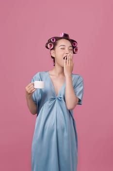 Morning coffee. Cheerful glamorous woman with hair curlers drinking hot drink holding cup,