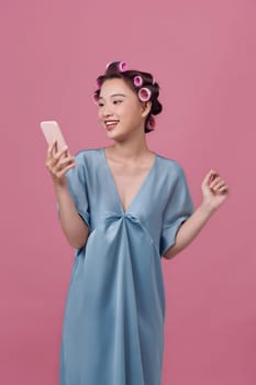 Portrait of attractive focused cheery woman wearing curlers using device smm media