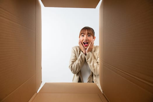 Happy laughing young woman putting arms into box, feeling excited receiving order from internet store