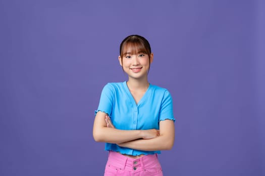 Young asian woman isolated on purple background with arms crossed and happy