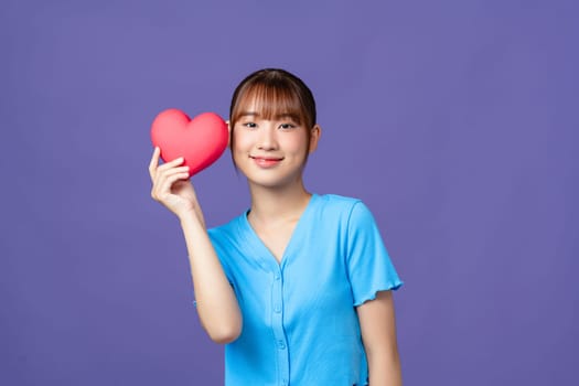 Beautiful woman holds red heart, isolated on purple background