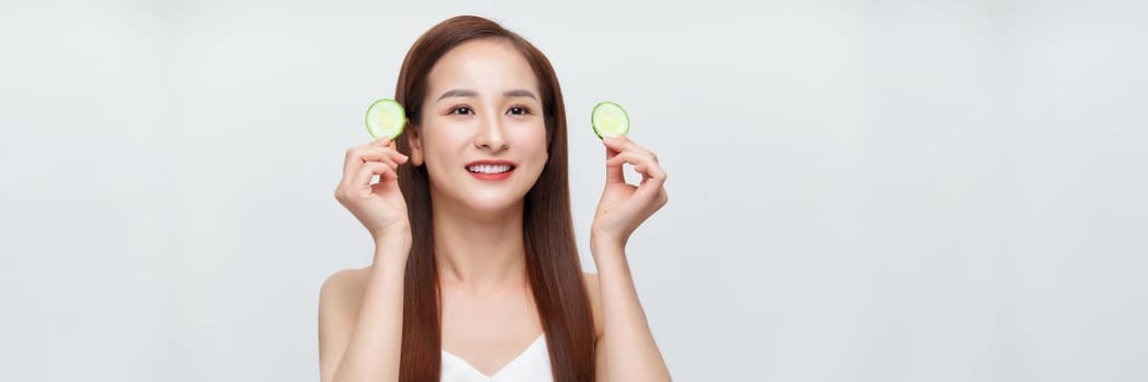 Banner of a gorgeous young woman holding cucumber slices while isolated on a white background
