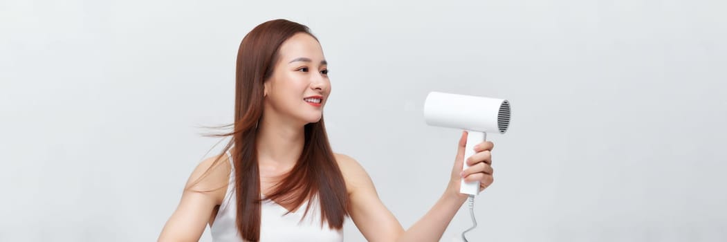 Crop of happy female using blow hair dryer. 