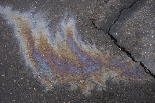 Leakage of oil or gasoline from the car on the asphalt in the parking lot. The concept of environmental pollution.