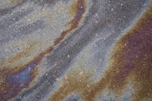 Textured stain of fuel or oil on wet asphalt on a rainy day.