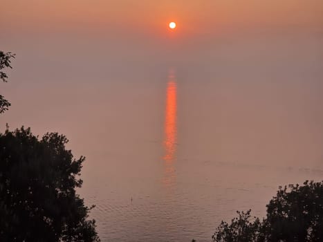 A sunset red sun rays trail on the sea