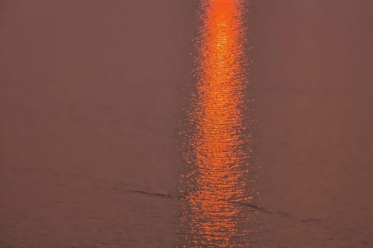 A sunset red sun rays trail on the sea