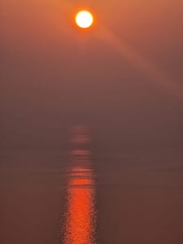 A sunset red sun rays trail on the sea