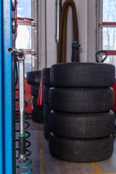 A set of tires for seasonal replacement near the lift in the tire workshop. The concept of seasonal car tire replacement.