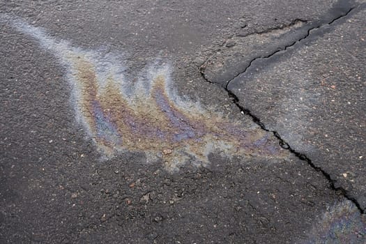 Leakage of oil or gasoline from the car on the asphalt in the parking lot. The concept of environmental pollution.