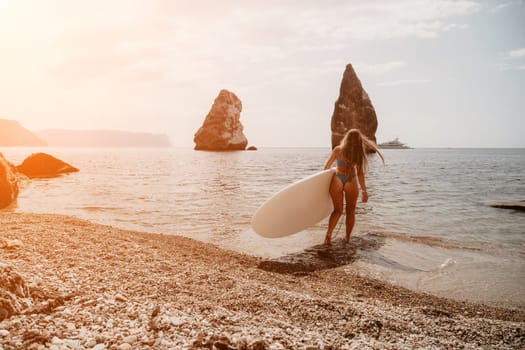 Close up shot of beautiful young caucasian woman with black hair and freckles looking at camera and smiling. Cute woman portrait in a pink bikini posing on a volcanic rock high above the sea