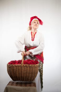 Cheerful funny adult mature woman solokha in a red knitted shawl. Female model in clothes of national ethnic Slavic style. Stylized Ukrainian, Belarusian or Russian woman poses in comic photo shoot