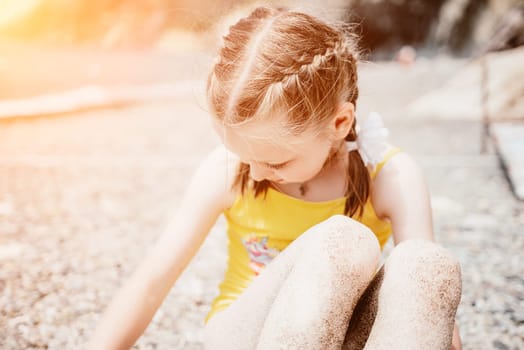 Cute little girl running along the seashore against a clear blue sea and rejoices in the rays of the summer sun. Beautiful girl in yellow swimsuit running and having fun on tropical beach