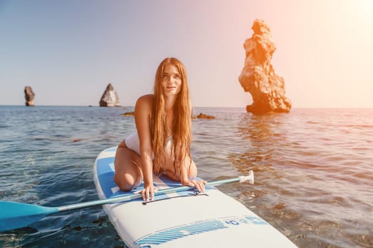 Close up shot of happy young caucasian woman looking at camera and smiling. Cute woman portrait in bikini posing on a volcanic rock high above the sea