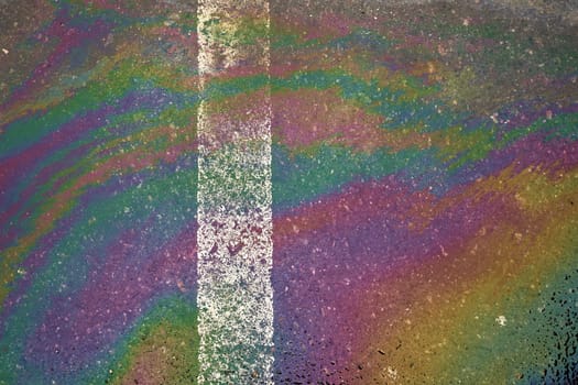 Oil, gasoline, or oil spill on wet asphalt with a parking lot and a dividing line