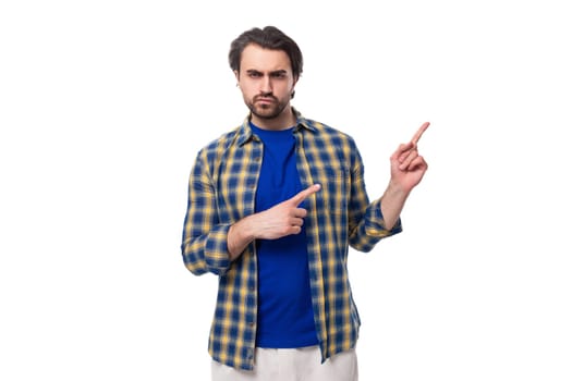 a well-groomed brunette brutal man with a beard in a plaid shirt holds his hand pointing to the side for space for news.