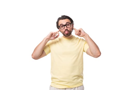 caucasian guy with a beard in glasses dressed in a light t-shirt closed his ears.