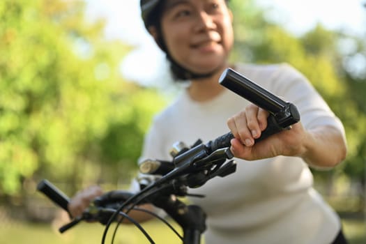 Happy senior woman in helmet riding bicycle in park. Healthy lifestyle concept